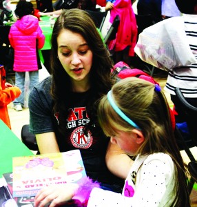 Abby Nelson (15) helps a student from Madison Elementary open her present from Santa Claus.