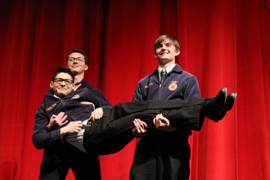 Seniors Jesse Mongan and Matthew Jones carry out Neo Orosco on stage to flex their muscles for buyers.