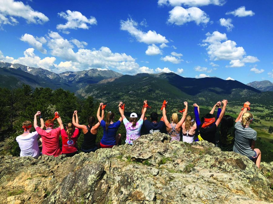 Conferees raise arms in victory after tackling a team building hike at the YMCA of the Rockies. Climbers scaled the mountain wearing symbolic orange bandanas on their wrists.