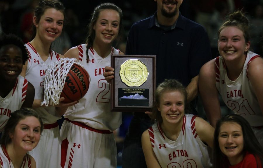 Moments after the district championship win, teammates Addie Randel, Nakaiya Kuskie, Gracie Schrebier, Bailie Duncan, Michaela Hill, Sydney Booth, and Anya Womack gather around the plaque.