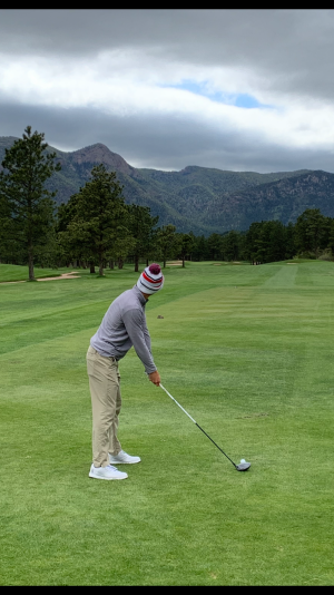 Walker Scott (20) tees with mountains in the distance
