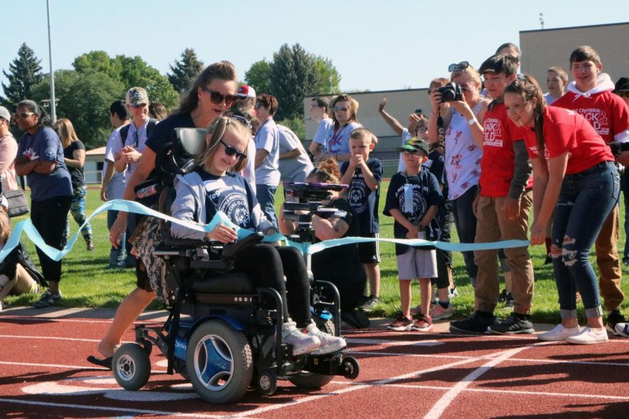 Participant in motorized wheelchair crosses the finish line